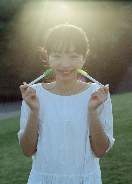 一个穿着白裙子的年轻女孩手里拿着牙刷站在草地上