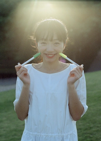 一个穿着白裙子的年轻女孩手里拿着牙刷站在草地上