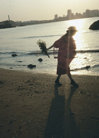 夕阳下 一个男子和一个女子在沙滩上行走 太阳正在落下。