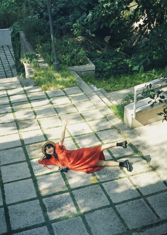 一位穿着红裙子的年轻女子躺在人行道上 双臂伸展。