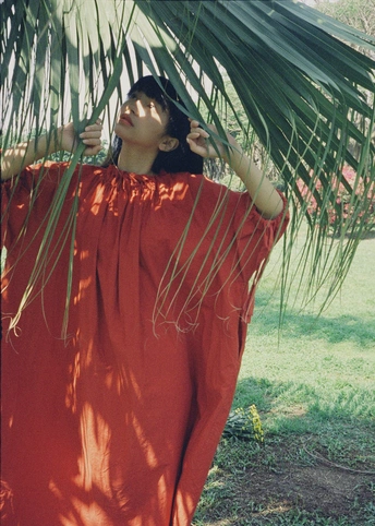 一位穿着红色连衣裙的女士站在棕榈树下面