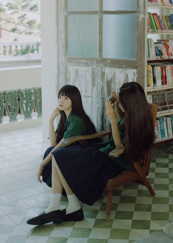 一个年轻女孩坐在椅子上 对着房间的窗户看镜子。