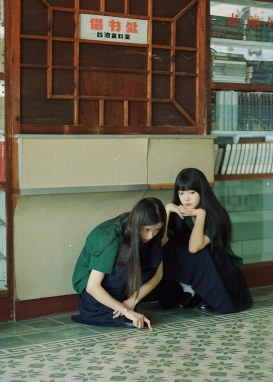 两位年轻女性坐在建筑物前地上。