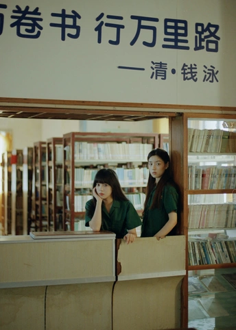 一些女性坐在图书馆桌子旁 桌子上堆满了书。