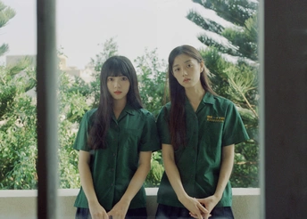 两个穿绿色军装的年轻女子站在一扇窗户前