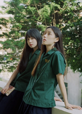 一些年轻女性穿着绿色衬衫站在彼此相邻的墙边。