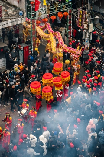 一条街道上有一大群人 中间有一个红龙在游行。