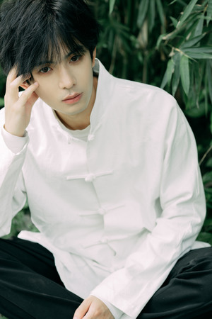 一个黑头发、穿着白衬衫的年轻人坐在外面