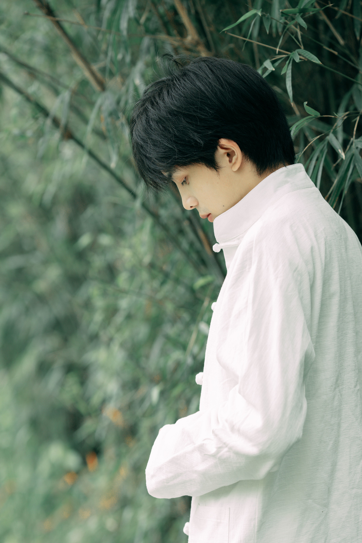 一个穿着白衬衫打着领带的年轻人站在一棵树前