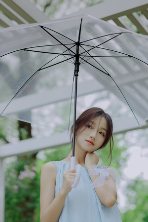 一位穿着蓝色连衣裙的年轻女子拿着一把黑色雨伞