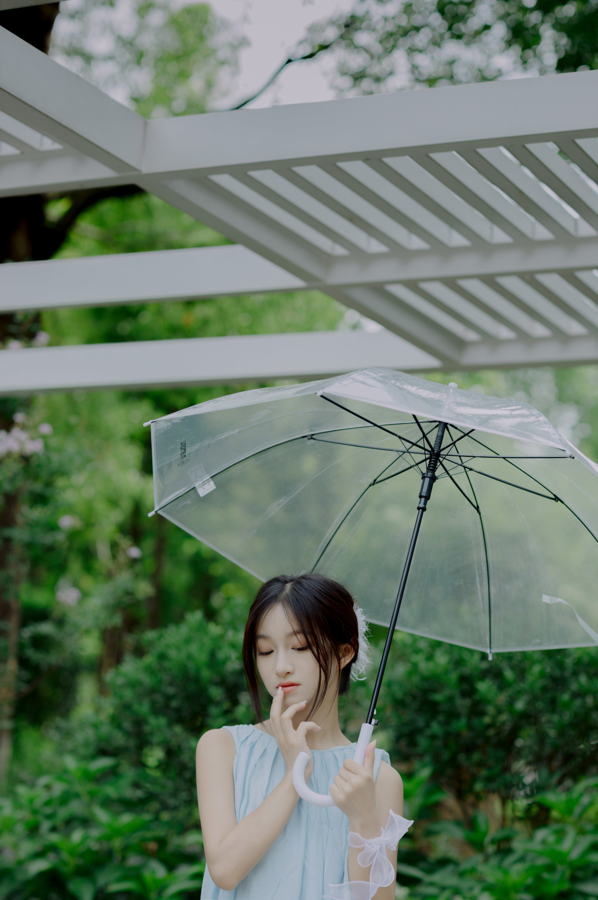 一位穿着蓝色连衣裙的年轻女子手持一把透明伞。