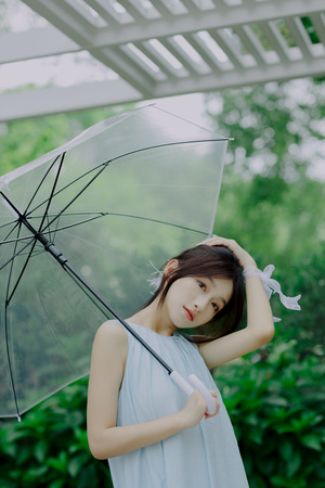 一位穿着蓝色连衣裙的年轻女子拿着雨伞