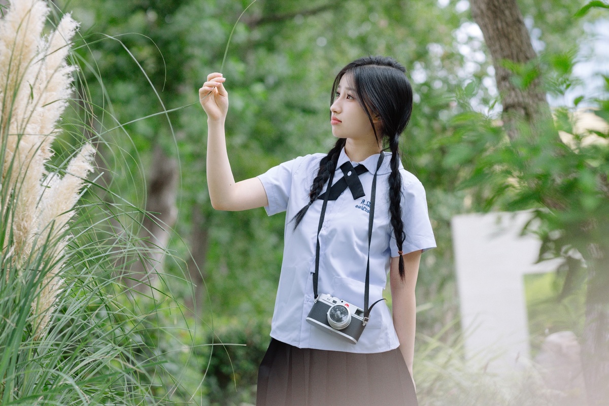 一位站在草地上拿着相机的女孩