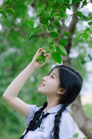 一位年轻女子在森林中拿着绿色植物