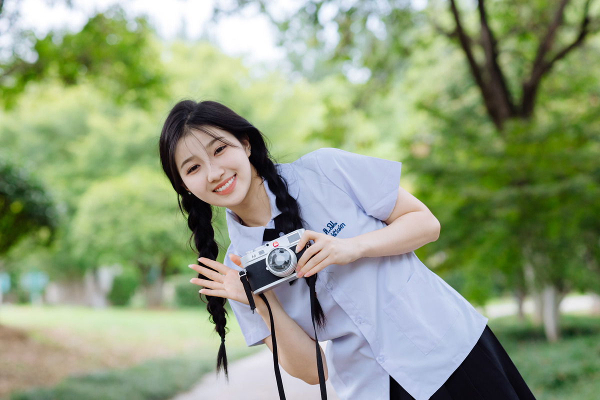 一位年轻女子在公园里拿着相机
