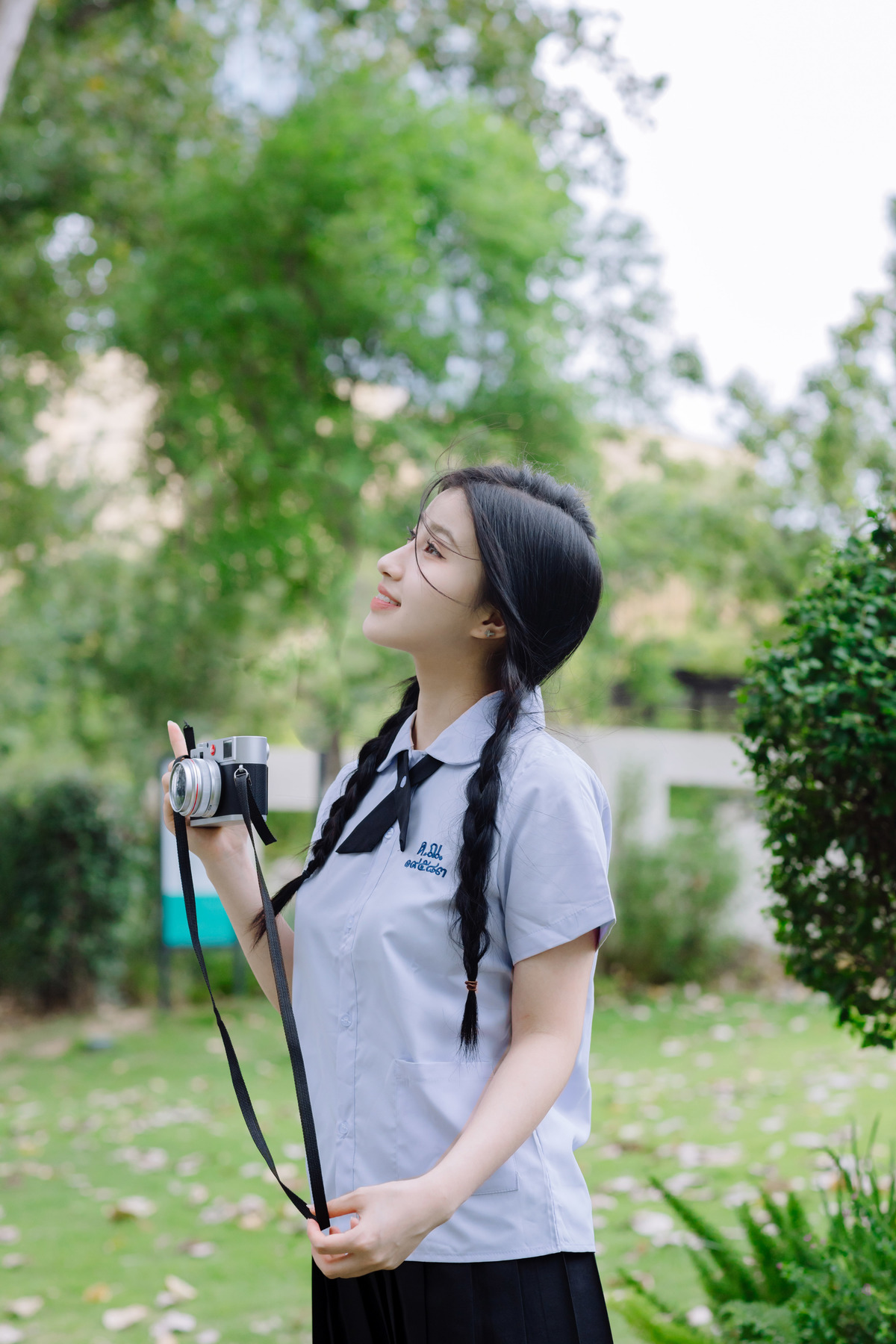 一位穿制服的年轻女子手持相机站在公园里