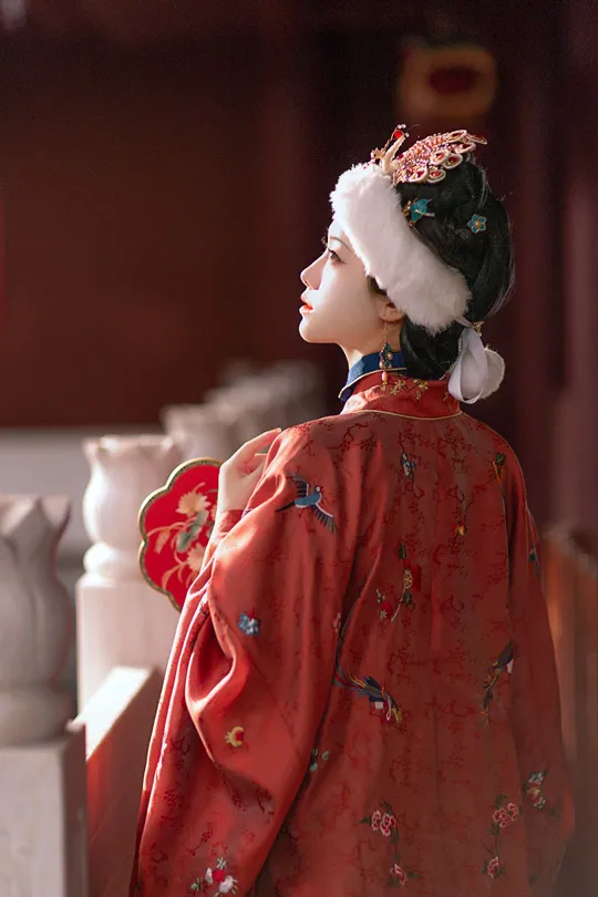 一个穿着红传统服装的女人 戴着帽子 手里拿着一个玩偶