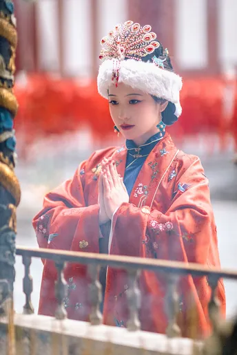 一个小女孩穿着传统的中国服装看着一个穿着红裙子和帽子的年轻人