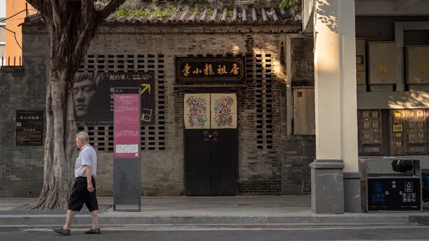 一个人和一个女人正在一条人行道上行走 前方是一座老建筑。