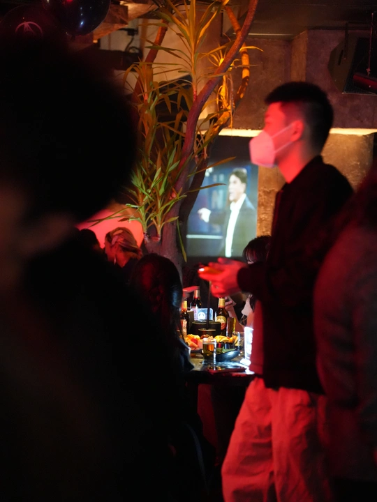 一个站在有其他人正在喝酒的房间里 前面有电视的男人