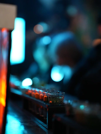 一个光线昏暗的房间 有电视、遥控器和一杯饮料。