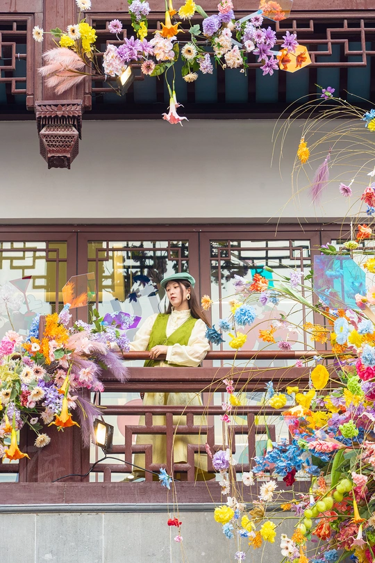 站在一栋建筑前拿着花的女士