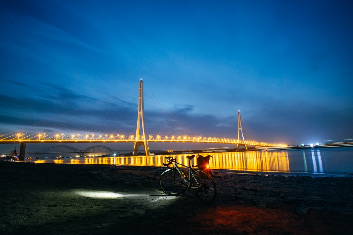 夜晚停在发光桥前的沙滩上的自行车