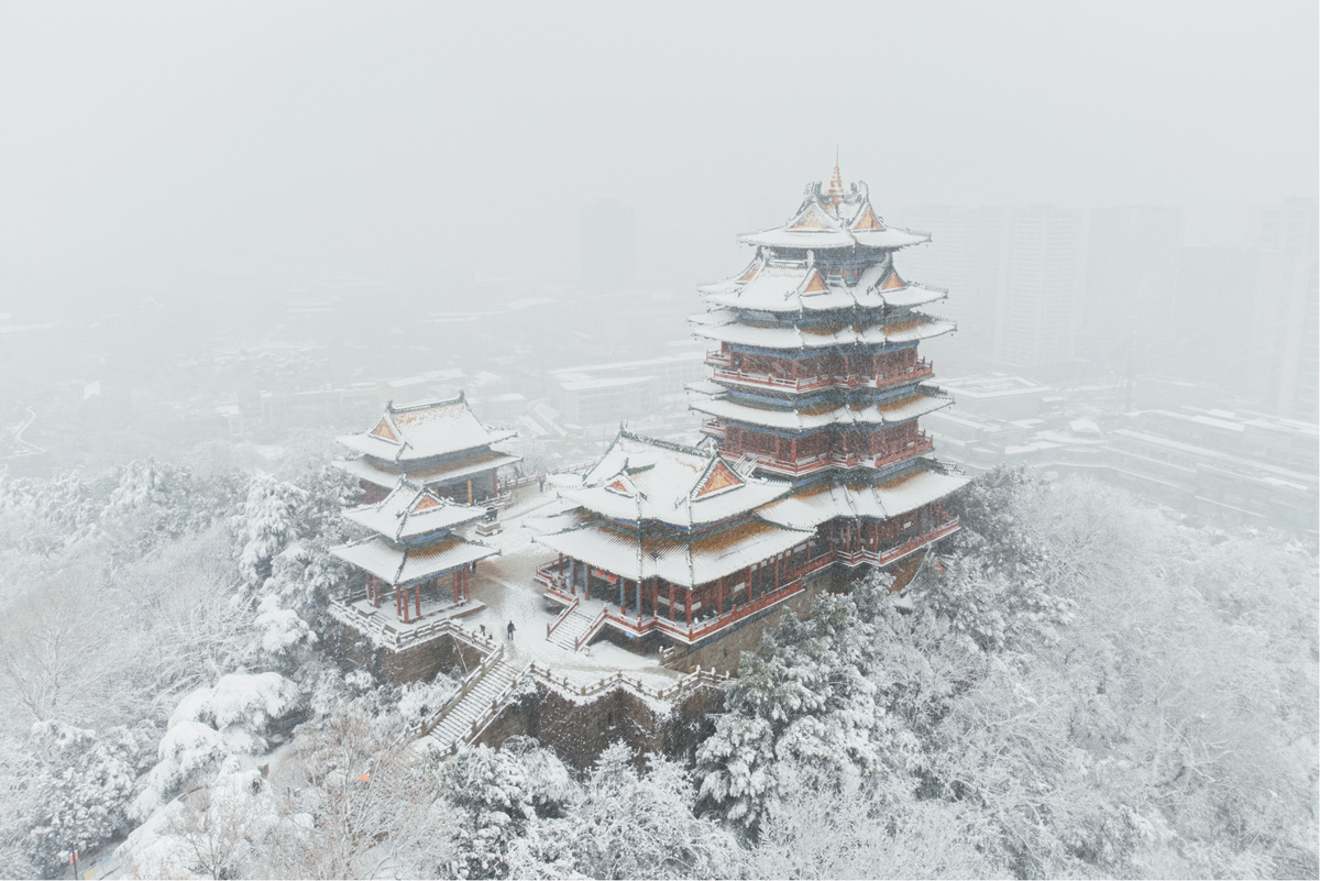 一座雪覆盖的城市山峦在冬季 前景是一座塔或寺庙。