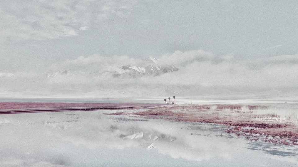 一个人站在海滩上 天空中是水和山。