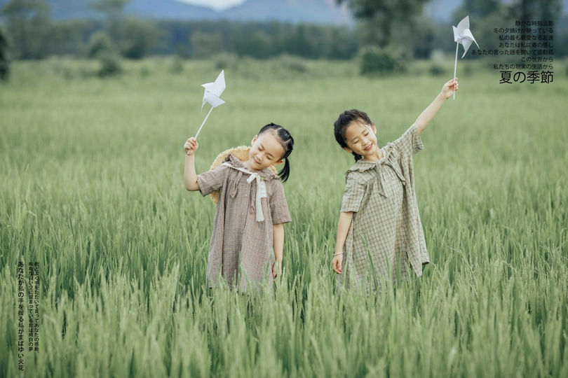 一个年轻女孩抱着一个小女孩站在绿色的麦田里