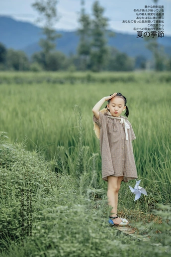 一个穿着连衣裙的小女孩站在绿草地里