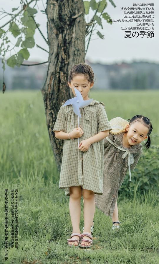 两个小女孩在树旁的田野里玩耍