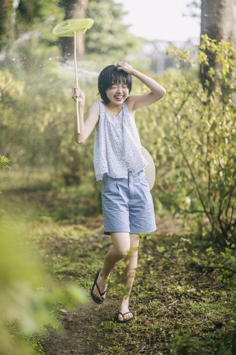 一位年轻女子手持雨伞穿越森林