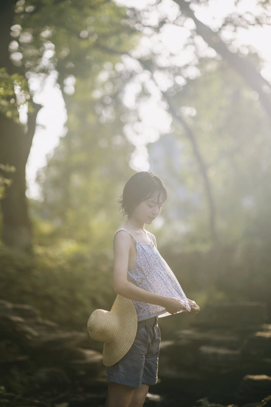 一个戴草帽的年轻女子穿过森林 抱着一个小女孩。
