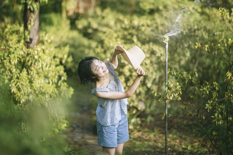 一个小女孩在给一棵年轻的树上喷水。
