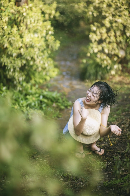 一位穿着连衣裙的年轻女子在森林或树林中的溪流中玩耍