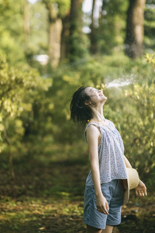 一个小女孩站在森林里 从水管喷水给一个小男孩