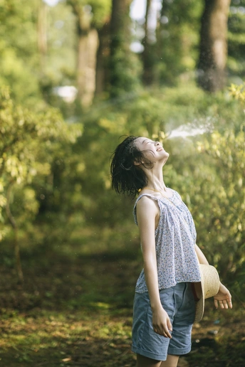 一个小女孩站在森林里 从水管喷水给一个小男孩