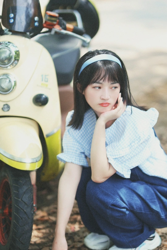 一个年轻女孩坐在黄色滑板上 旁边是地面。