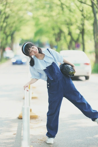 一位年轻女子靠在人行道上的杆子上