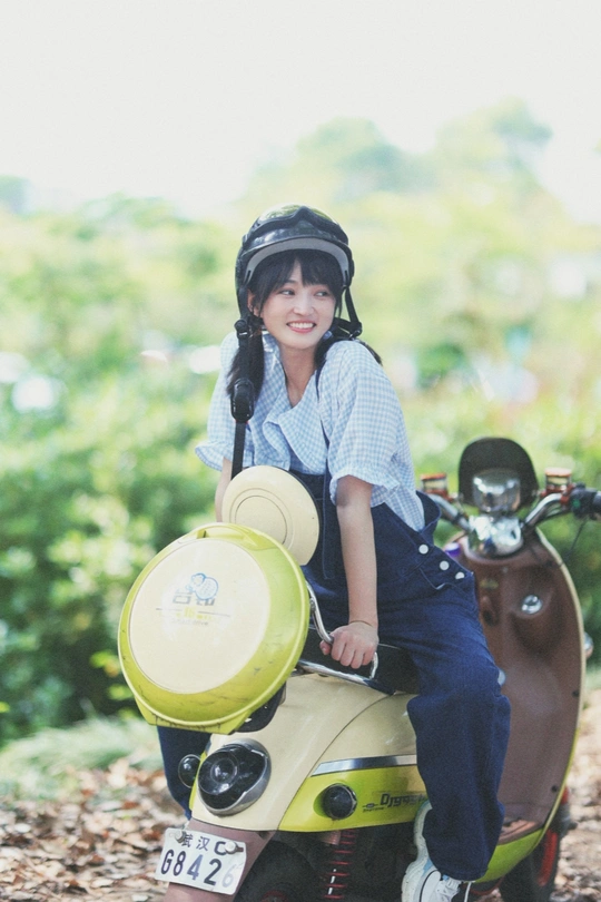 一个戴头盔的男孩坐在小型摩托车上 小女孩坐在上面。