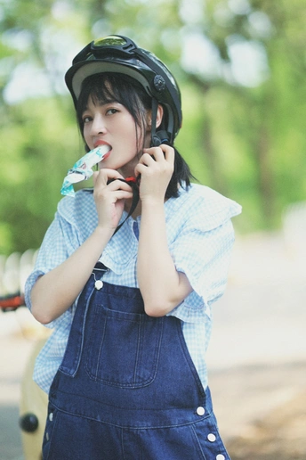 一个穿着工作服和头盔的年轻女子正在刷牙