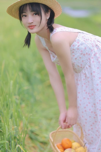 一位穿着连衣裙和草编帽子的年轻女子抱着一个装满水果的篮子