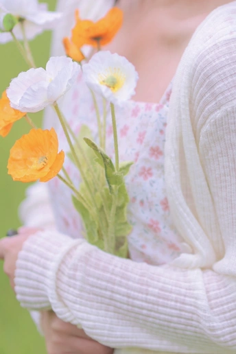 一位年轻女子抱着一束白橙花