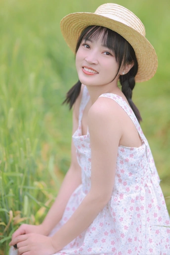 一位穿着白色连衣裙和草帽的年轻女子坐在草地上的一幅肖像画