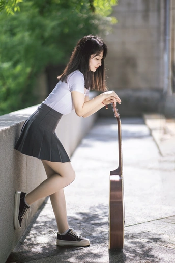 一位年轻女子抱着一把小提琴倚靠在墙上