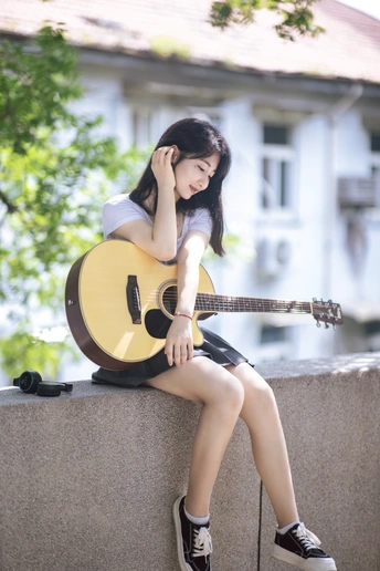 一个年轻女子坐在墙上弹吉他