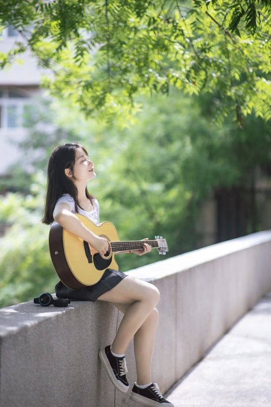 一个年轻女子坐在墙上弹吉他