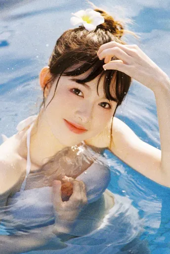 一个年轻女子在游泳池里 头发上有一朵花 头上有一朵花。