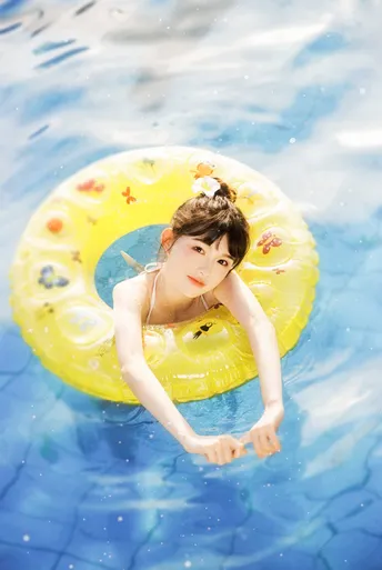 一位年轻女子在游泳池中游泳 水中有一个黄色的环